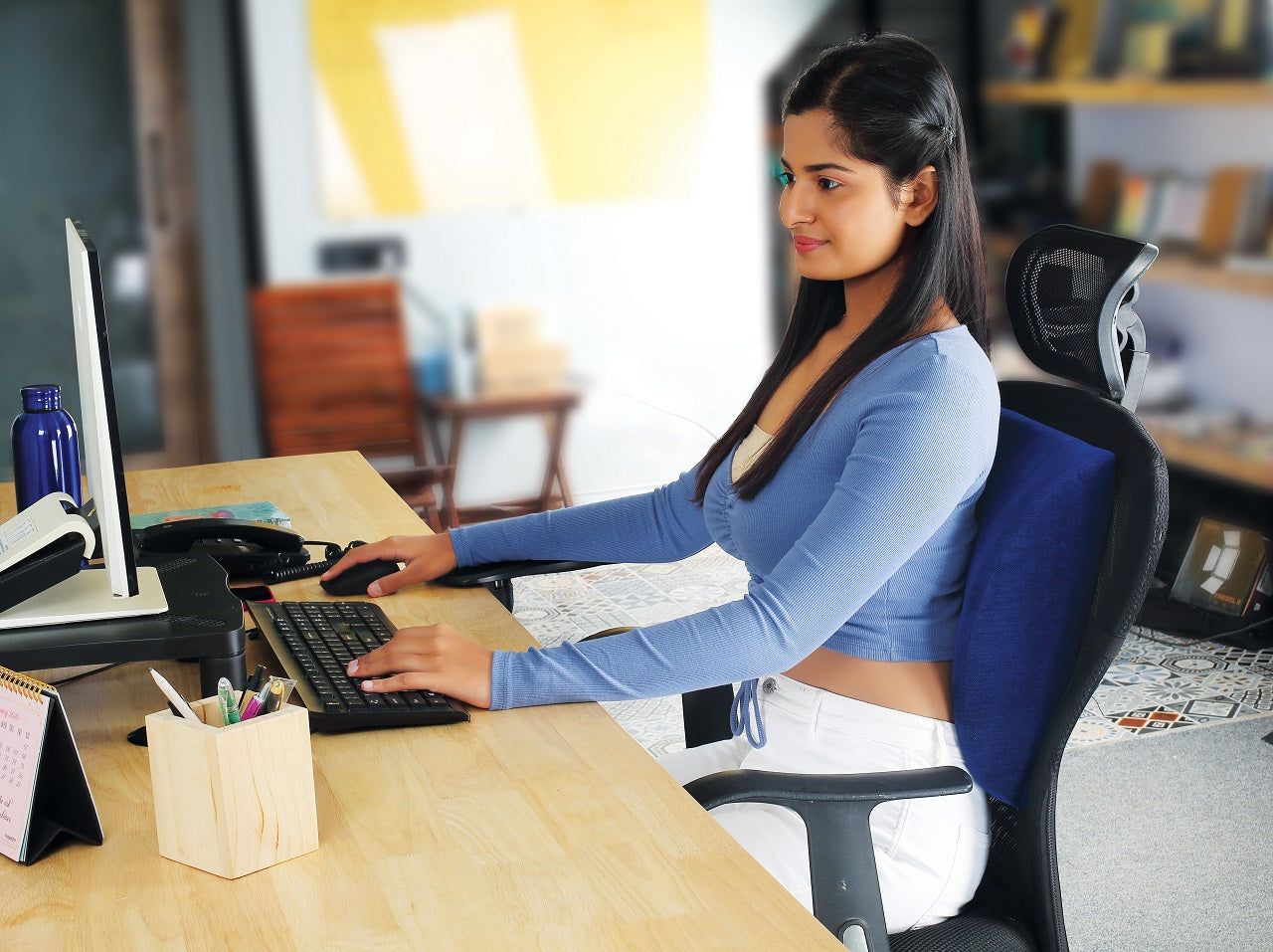 Professional working at office desk using ergonomic PALO backrest for support