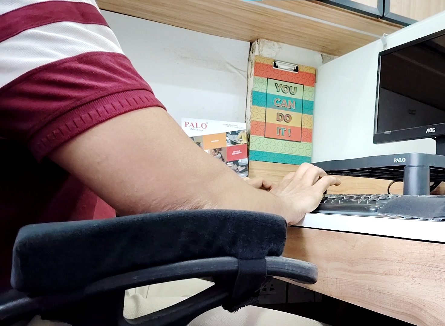 Office worker using PALO ergonomic armrest cushion for shoulder and wrist support while typing