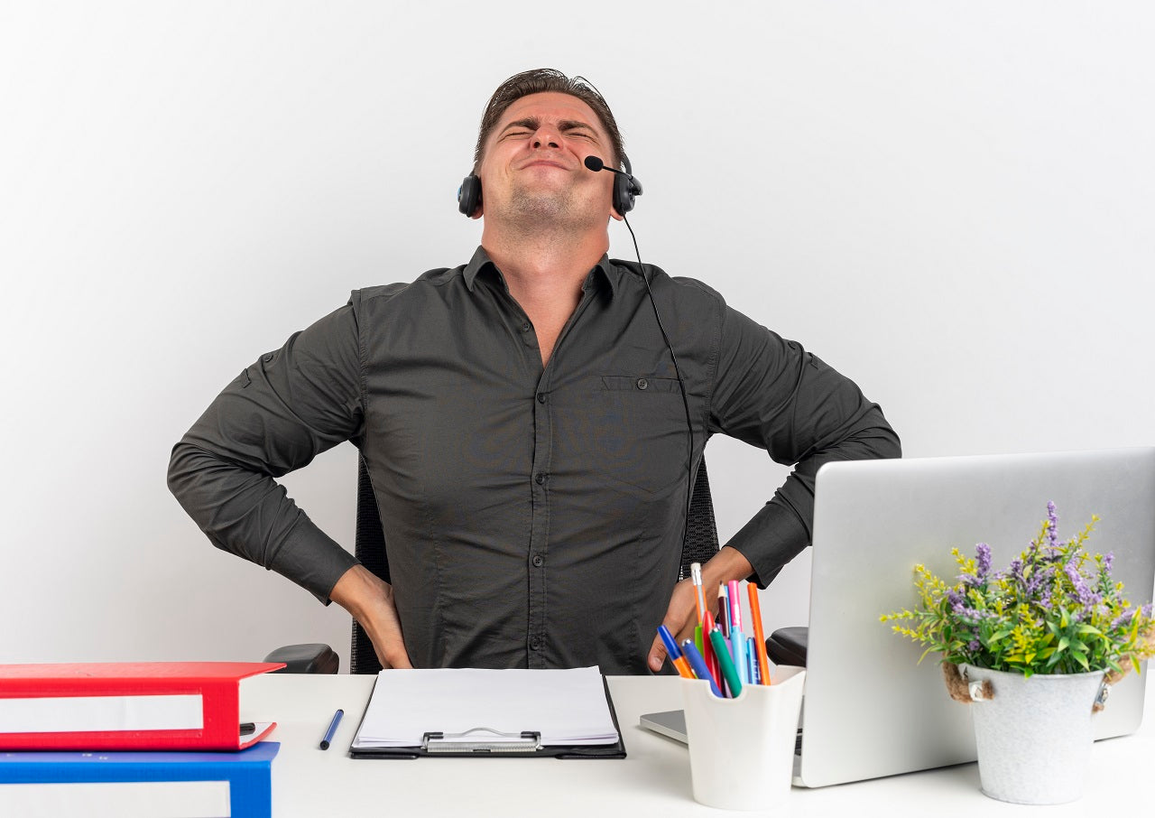 Employee with poor posture holding back in pain looking distracted at work