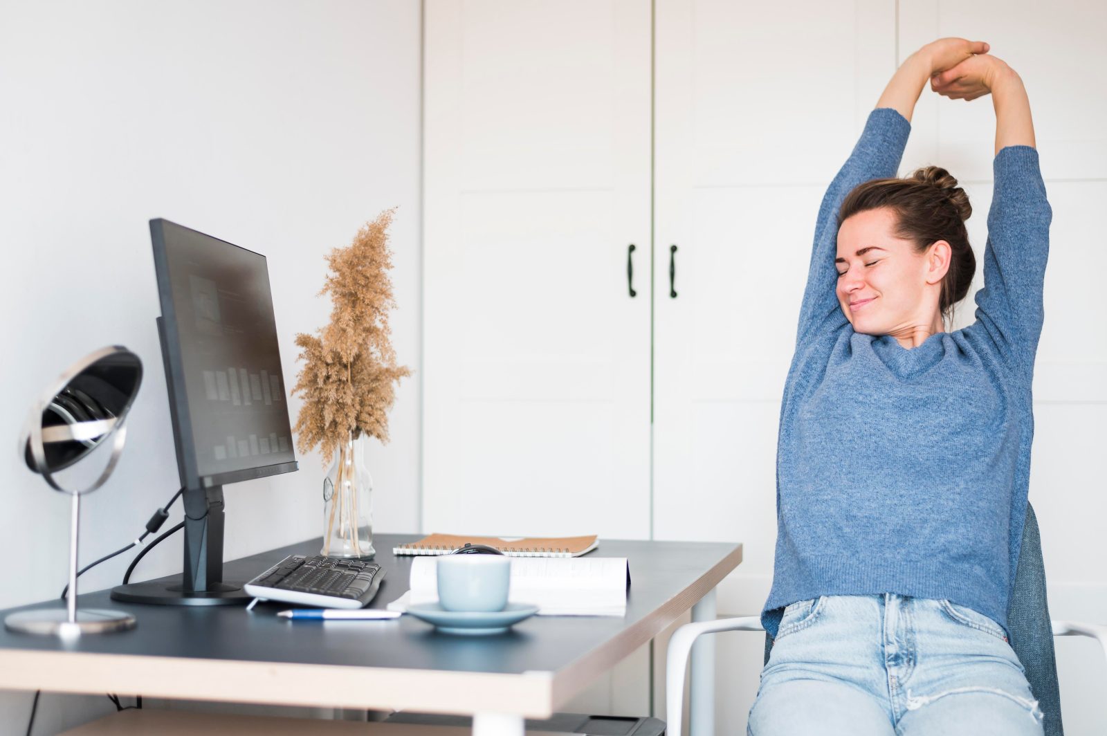 Person stretching at their work desk during a break to relieve body stiffness from long sitting hours
